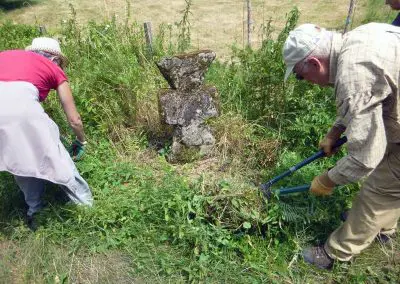 Photo d'une croix de Crozant en train d'être entretenue par des membres de l'association ASCTC pendant une action de débroussaillage.
