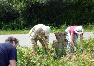 Photo d'une croix de Crozant en train d'être entretenue par des membres de l'association ASCTC pendant une action de débroussaillage.
